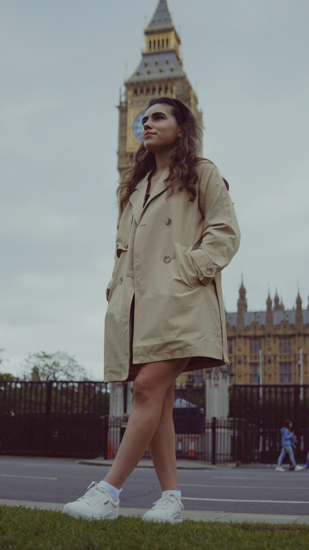 Girl in a trench coat walking past Big Ben in London